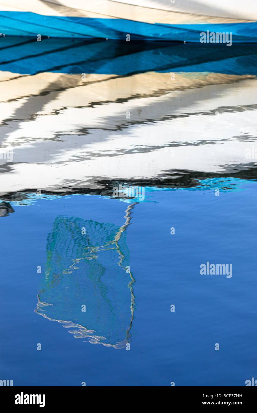 Reflection of a blue and white fishing boat on water, featuring ...