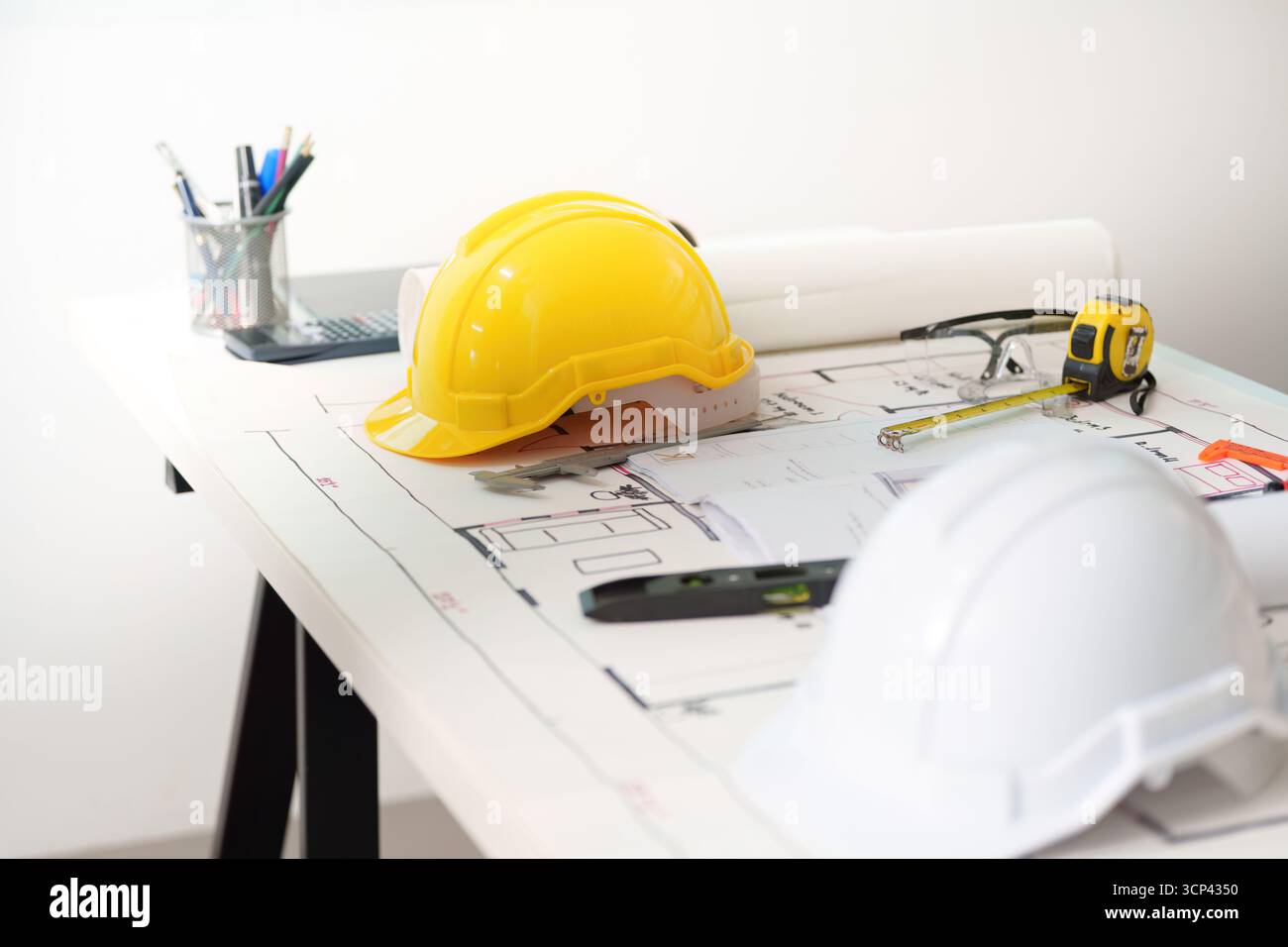 Engineer workspace. Construction helmets and blueprints on a desk for architectural projects. Stock Photo