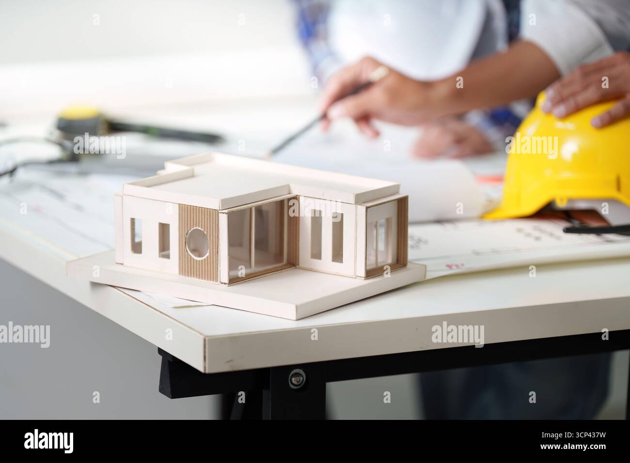 Architectural model on table with engineers discussing plans Stock Photo