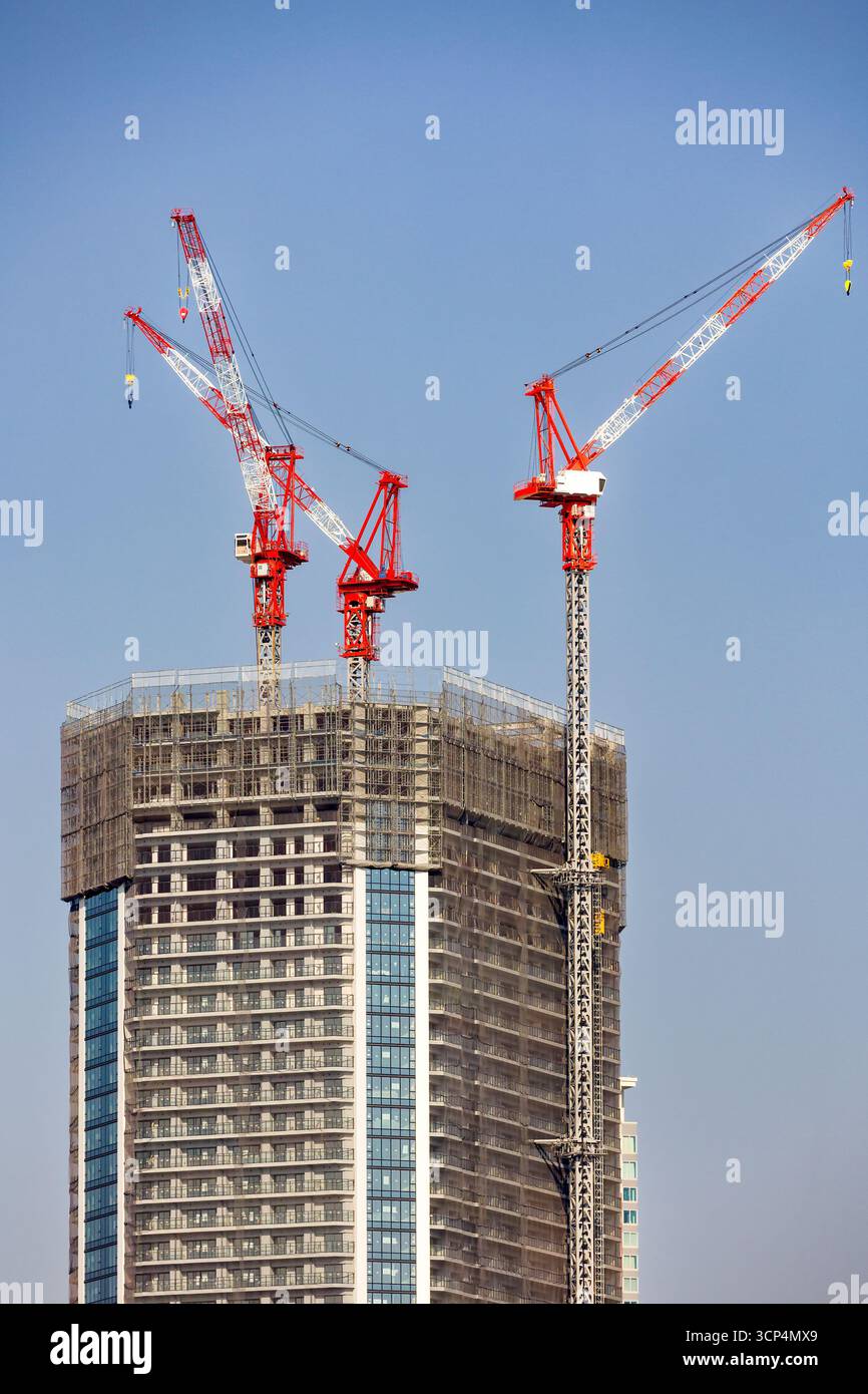 Construction site showing a modern skyscraper being built with tower cranes Stock Photo