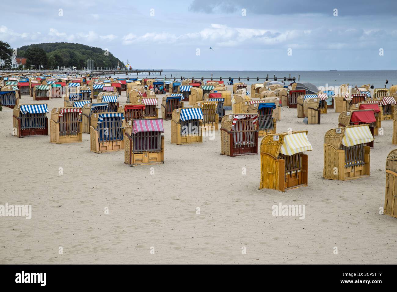 Traditional roofed wicker beach chairs on the white sand beach on overcast summer day, Travemunde Strand, Travemunde, Schleswig-Holstein, Germany Stock Photo