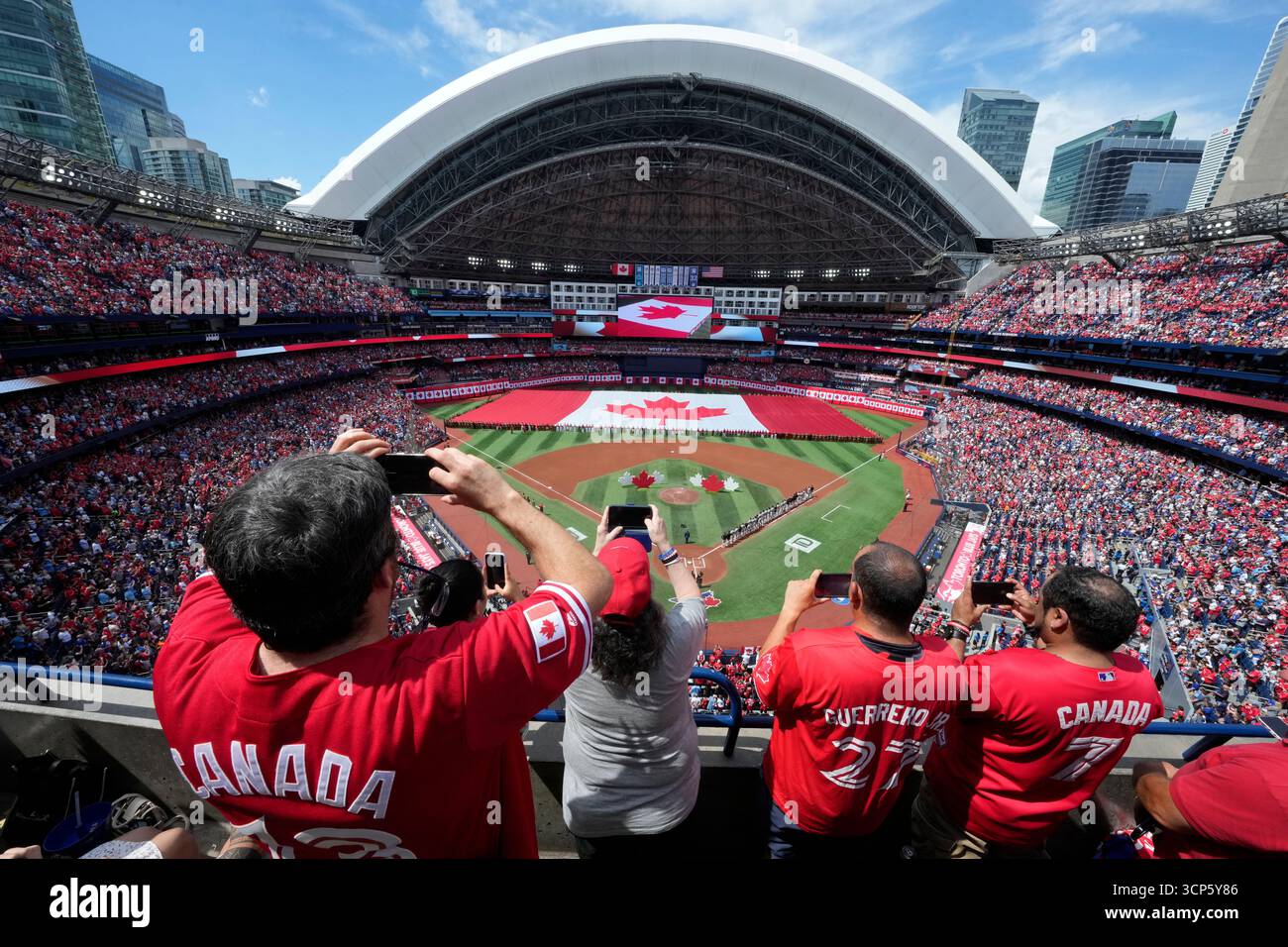 Fans take photos as a large Canadian flag is unfurled before the start ...