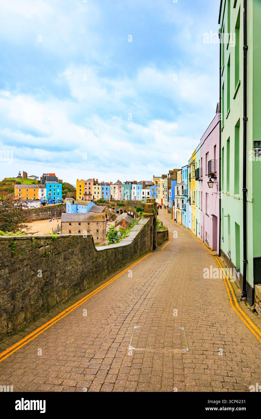 The narrow, cobbled Crackwell Street leads down to the multi-coloured houses around the harbour in Tenby, Pembrokeshire, South Wales, UK Stock Photo