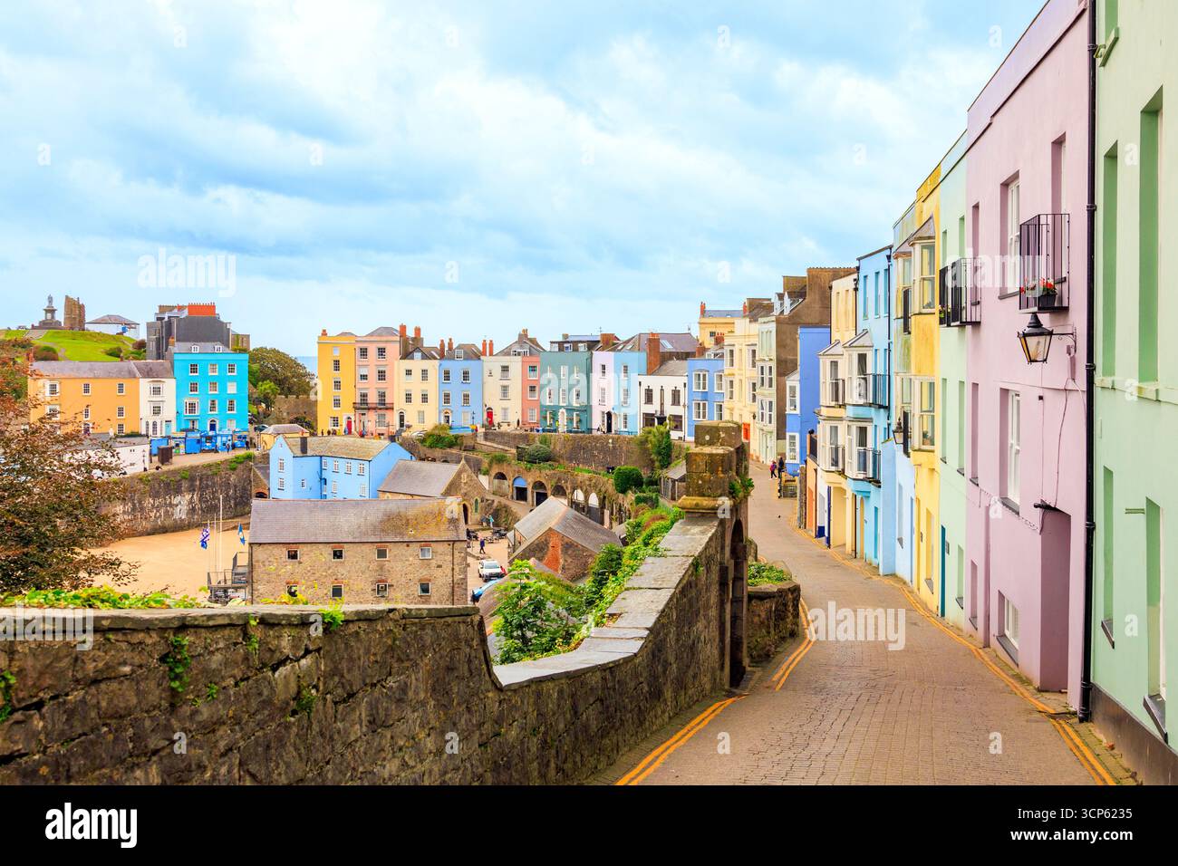 The narrow, cobbled Crackwell Street leads down to the multi-coloured houses around the harbour in Tenby, Pembrokeshire, South Wales, UK Stock Photo