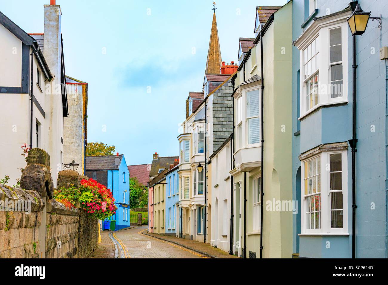 A colourful terrace of houses and St Mary's church in St Mary's Street, Tenby, Pembrokeshire, South Wales, UK Stock Photo