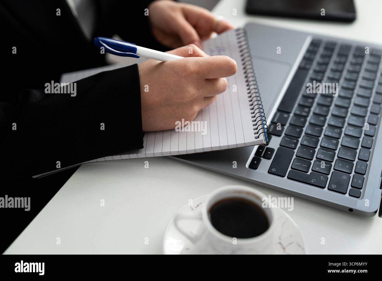 Tight crop of writing next to a laptop and cup. Suits content planning, study, copywriting, and productivity content.  Stock Photo
