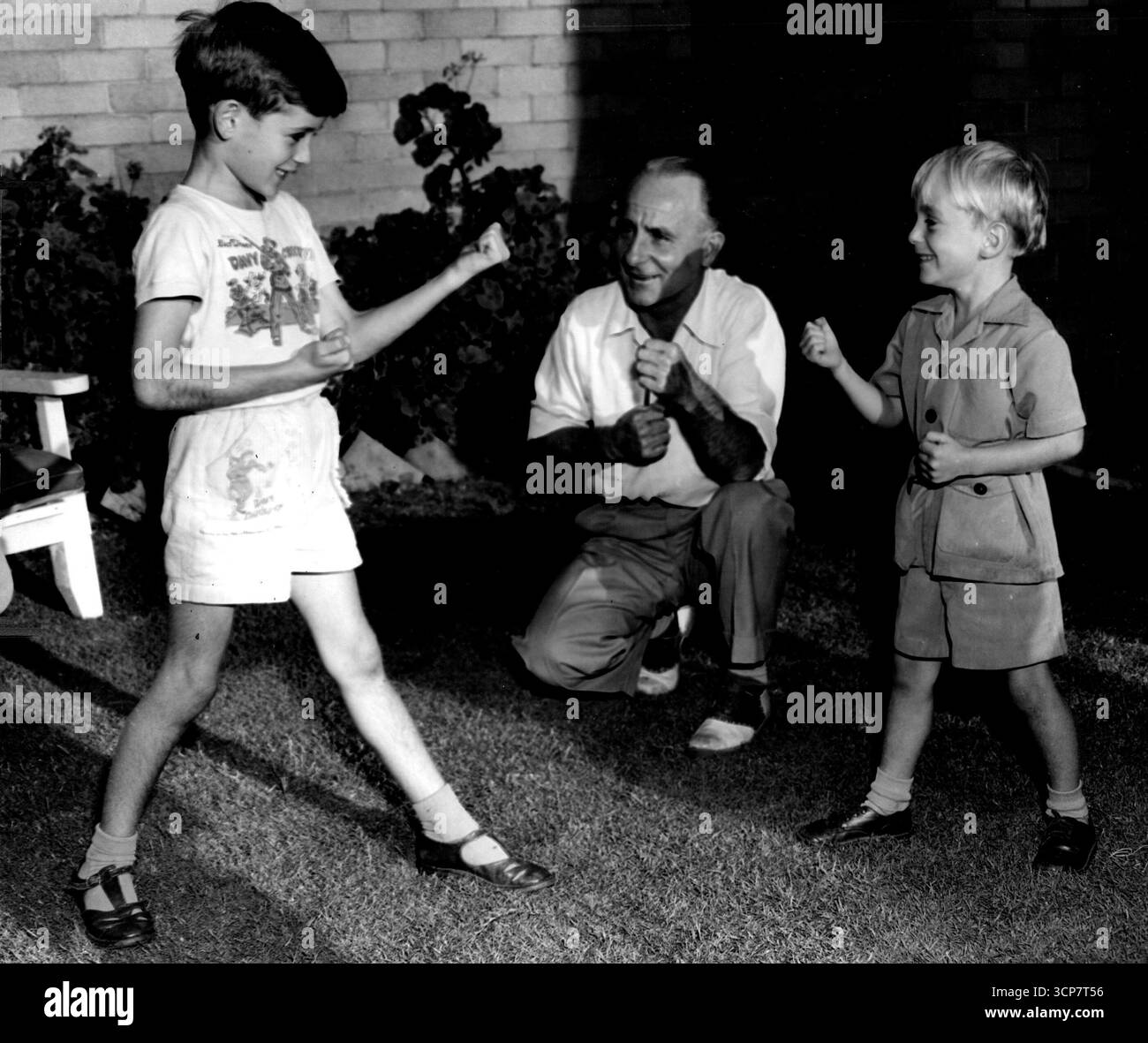 Billy Cook - Champion Jockey Billy Cook teaching his 2 sons William (on the left) and Peter how to box. Billy Cook trained regularly at Ern McQuillans Newtown Gymnasnm during the 1940-1950s.Billy Cook won 2 Melbourne cups Skipton 1941, Rainbird 1945.Peter Cook his youngest son also won 2 Melbourne cups.Just a dash 1981, Black Knight 1984. January 1, 1952. (Photo by Ern McQuillan). Stock Photo