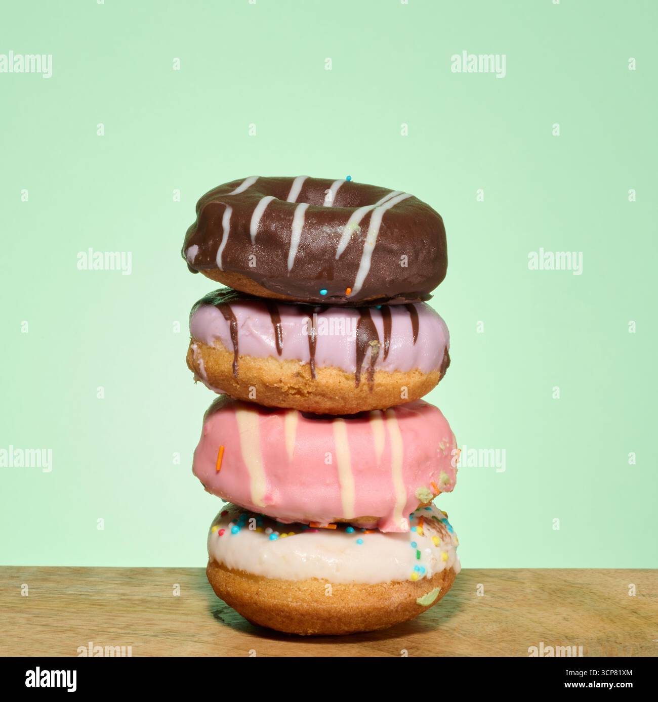 Stack of donuts with different toppings and glazes, green background Stock Photo