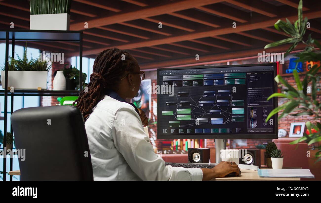 Teleworking computer scientist at home using PC to develop artificial intelligence self learning algorithms. African american woman working with AI machine learning software on PC, camera A Stock Photo