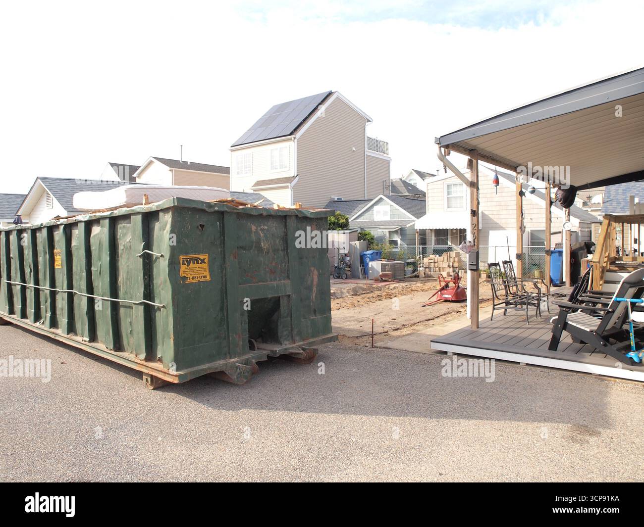 Large Dumpster alongside a vacant lot after building demolition. Stock Photo