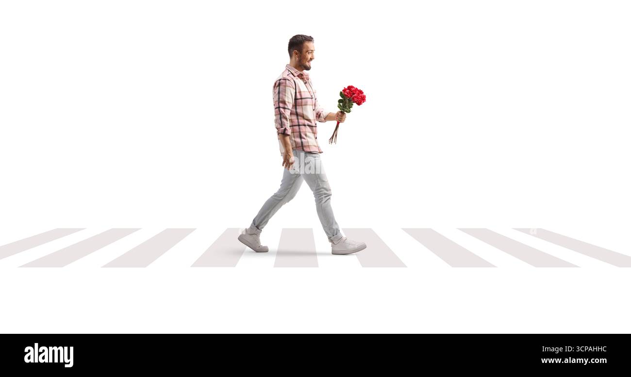 Full length profile shot of a man holding a bunch of red roses and walking at zebra crossing isolated on white background Stock Photo