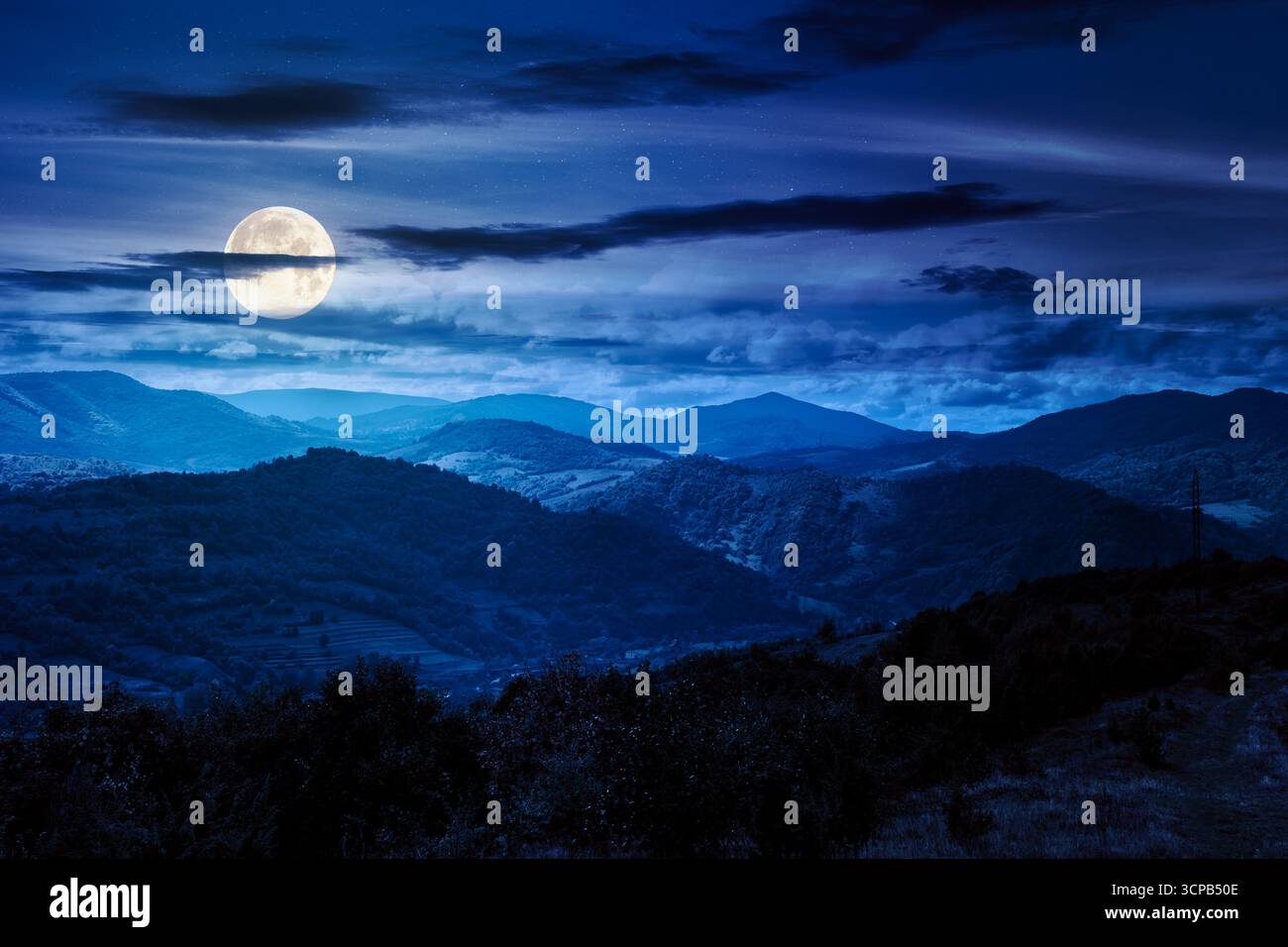 autumn landscape in mountains at night. beautiful view of countryside. colorful alps in the background. cloudy sky. picturesque rural scenery with vil Stock Photo