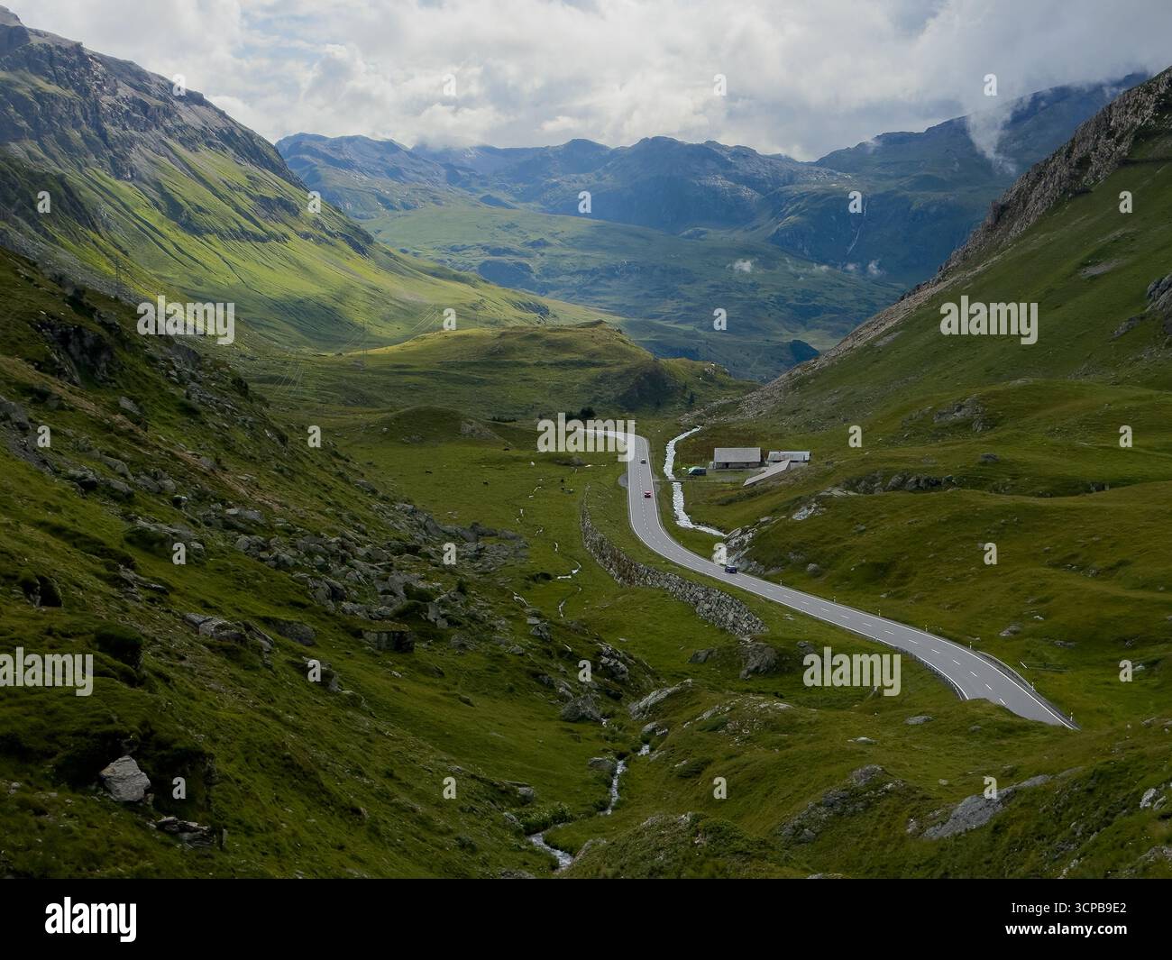 Aerial View Of A Winding Road Cutting Through The Lush Green Valley aerial-view-of-a-winding-road-cutting-through-the-lush-green-valley