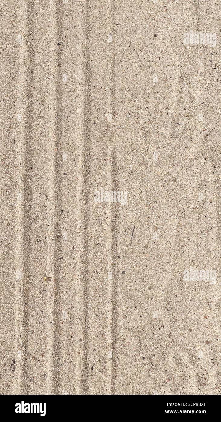 Close-up of textured sand with visible lines and patterns. The surface appears smooth and light beige in color, showcasing natural elements. Stock Photo