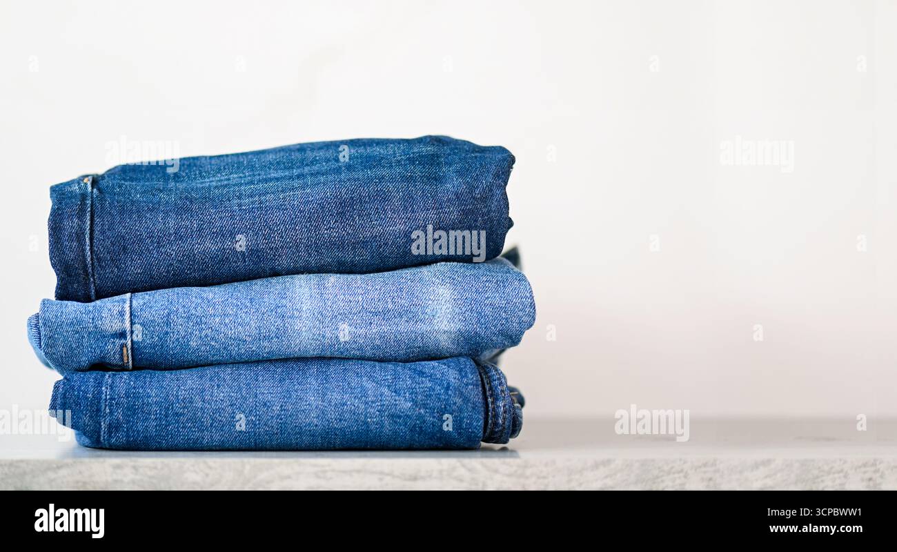 Stack of blue jeans on a shelf, space for text Stock Photo