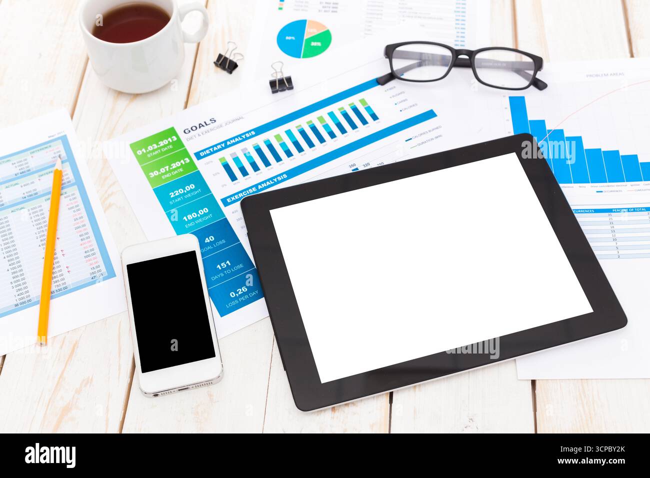 Office workspace displaying tablet, smartphone, documents, and coffee cup during work hours Stock Photo