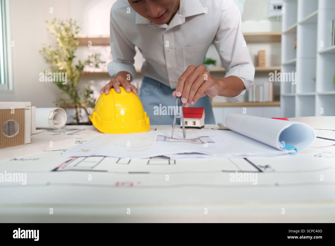 Using Compass In Civil Engineer design. Young engineer using a compass on blueprints for ...