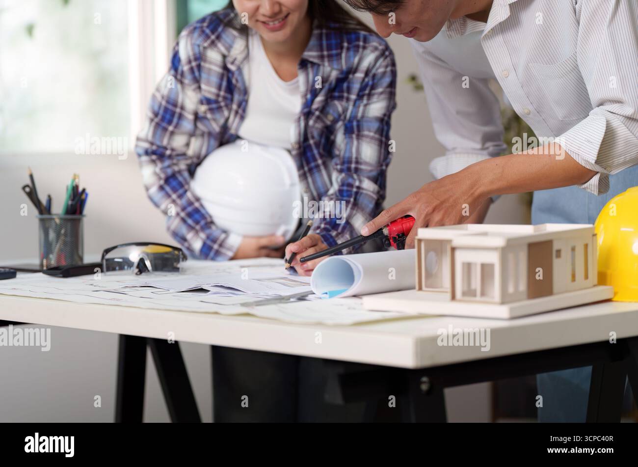 Engineer collaborating on architectural plans and model construction Stock Photo