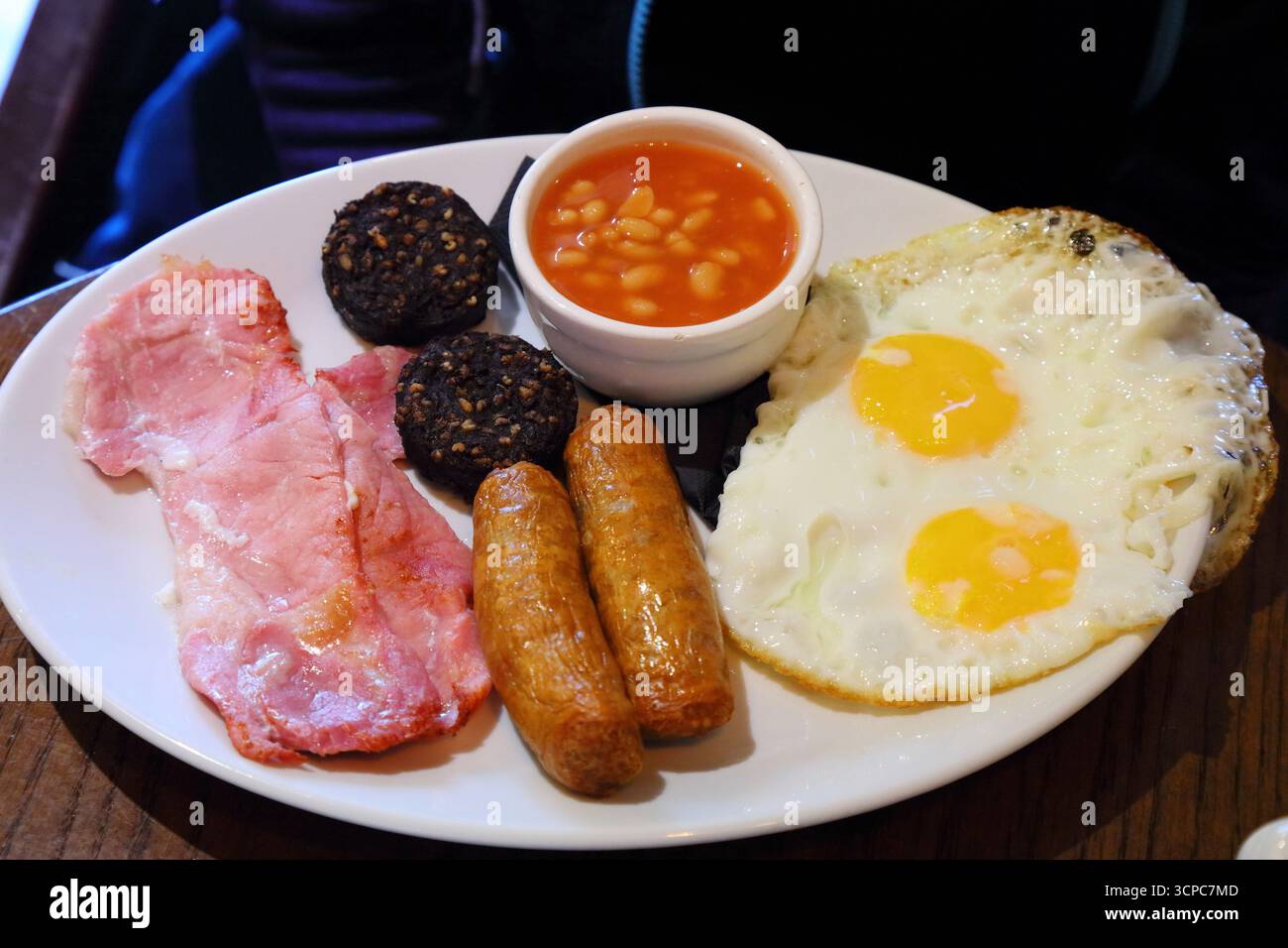 Irish breakfast. Traditional morning meal with sausage, bacon, pudding, fried egg and beans. Stock Photo