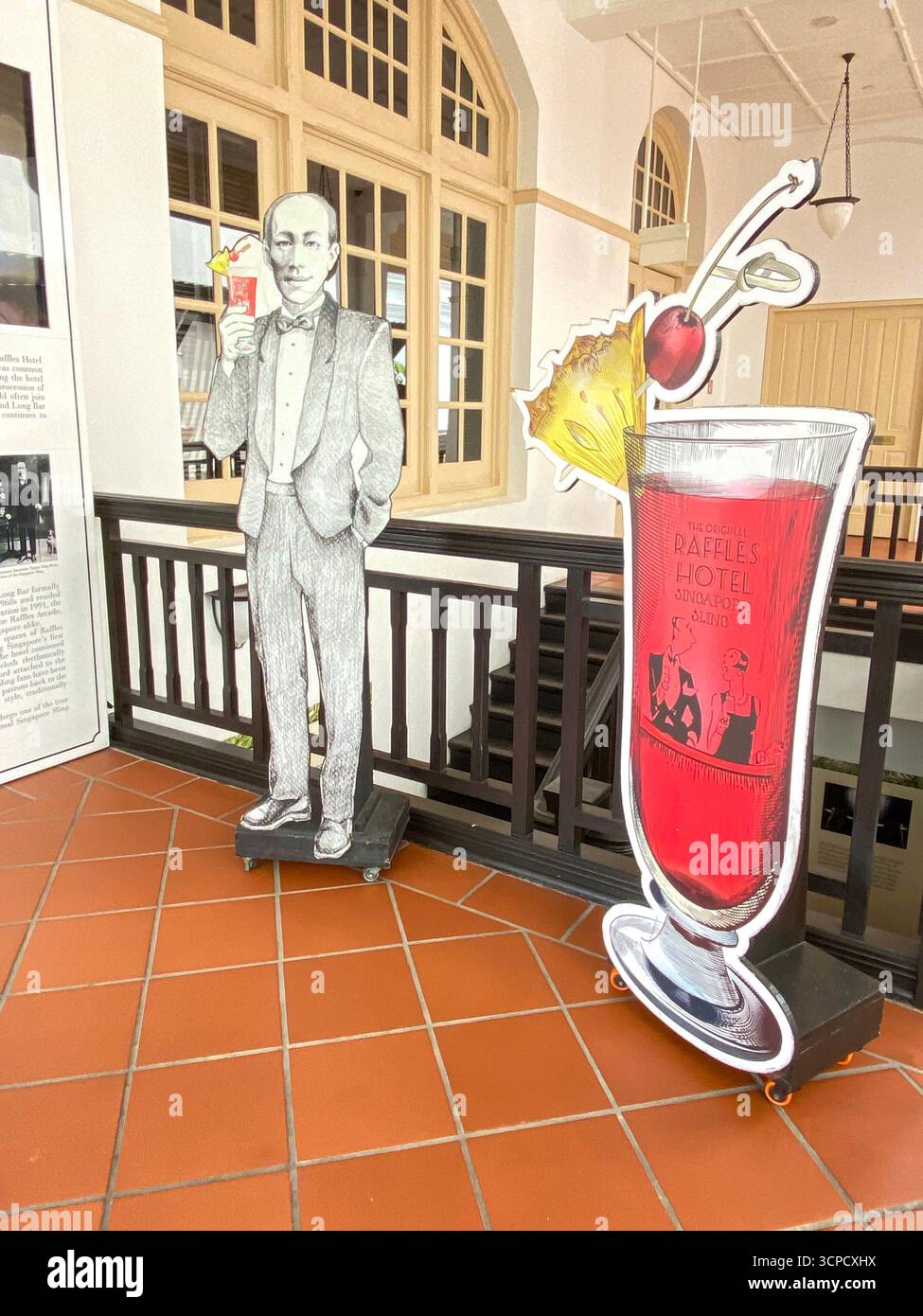 A large display board of a patron with his Singapore Sling at the entrance to the famous Long bar at the Raffles hotel in Singapore, - Smartphone Captured Stock Image
