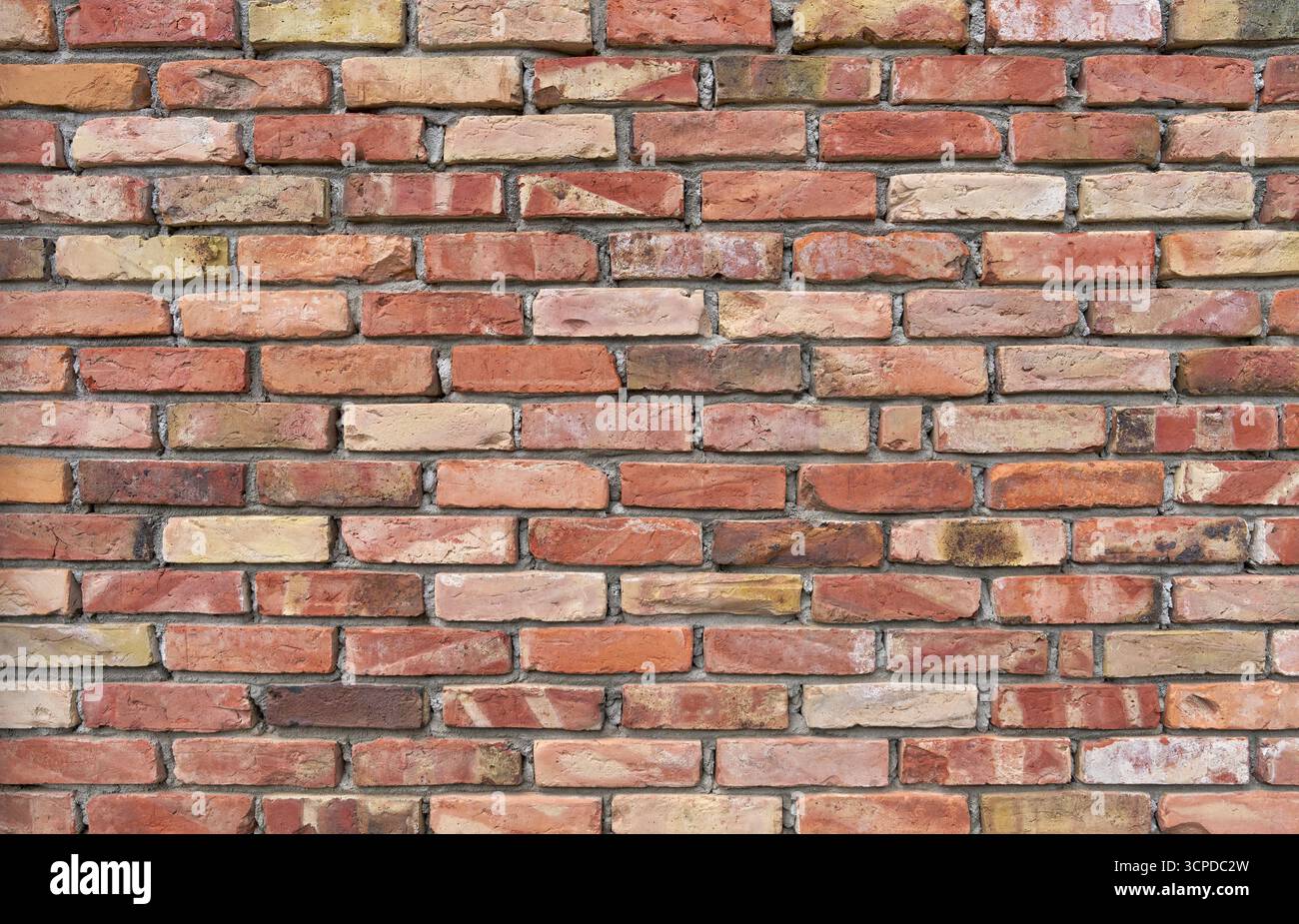 Brick wall made of old, differently colored clinker bricks with roughly worked mortar Stock Photo