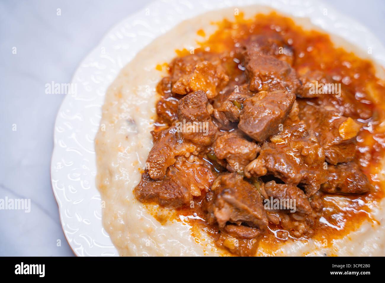 Traditional Turkish Hunkar Begendi food with creamy eggplant puree base. Made with tender meat served on white plate. Turkish anatolia cuisine concept Stock Photo