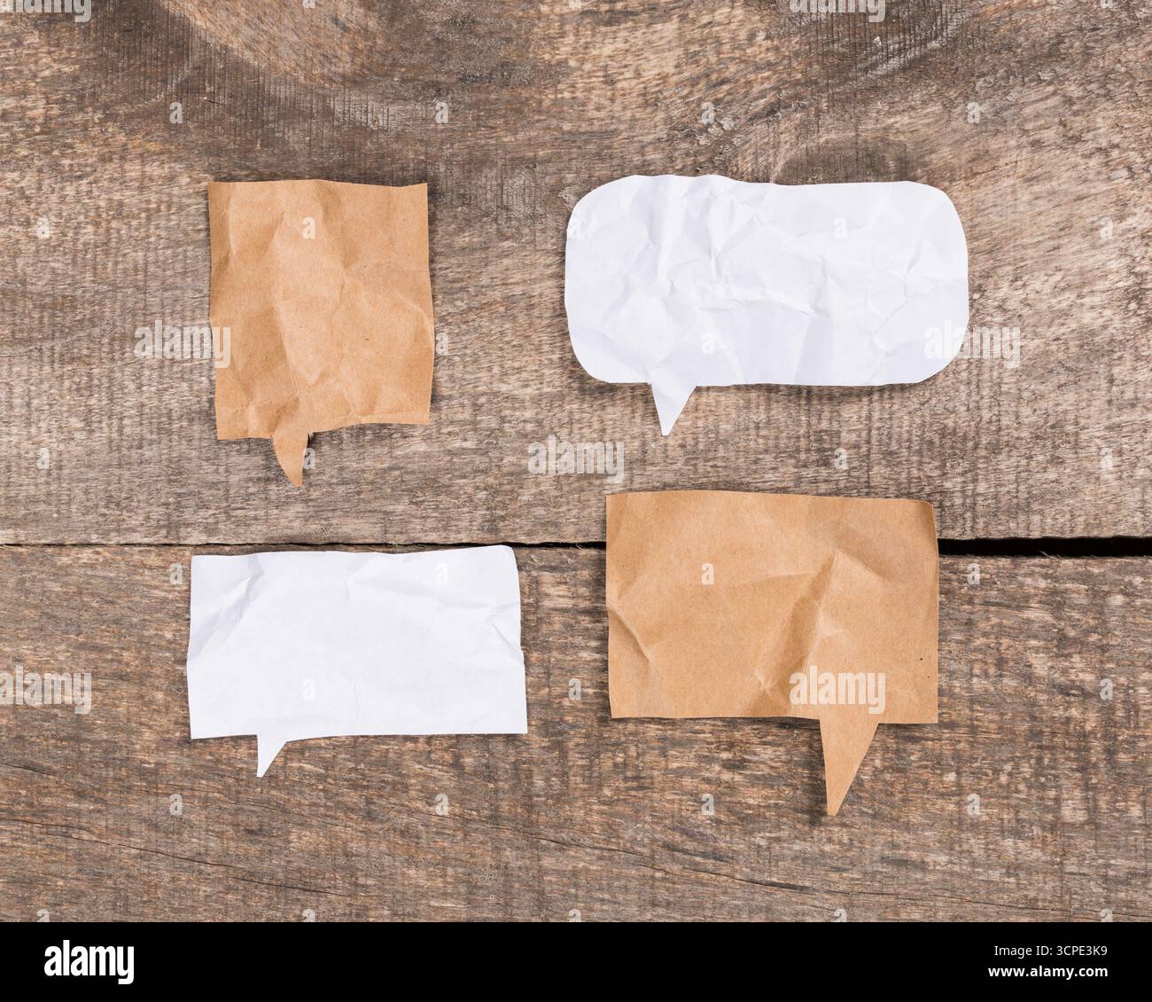 Empty speech bubbles on crumpled paper backgrounds on wooden surface Stock Photo