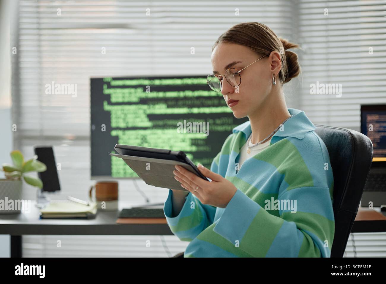 Young Woman Using Digital Tablet While Working in Modern Office Stock Photo