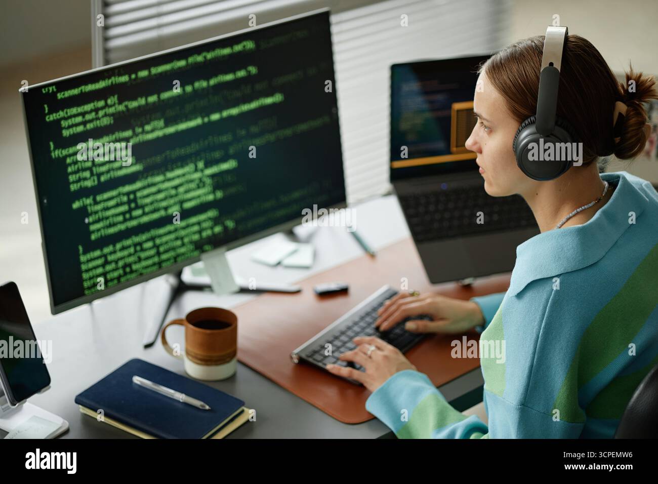 Young Woman Writing Computer Code on Desktop Computer at Workplace Stock Photo