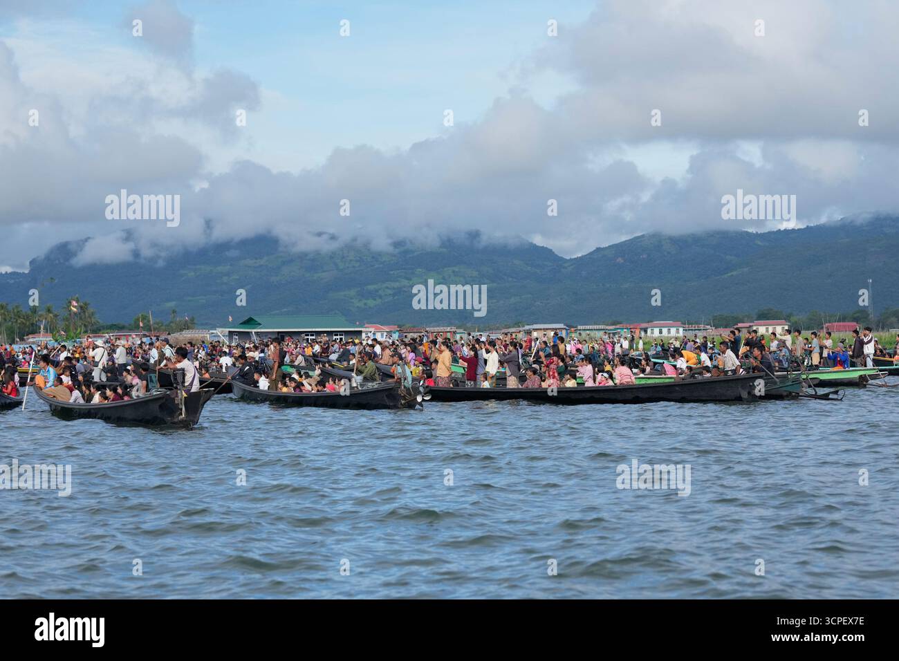 People watch while Intha ethnic people row on a long boat in a ...