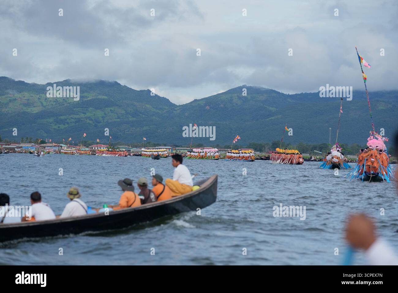 People watch while Intha ethnic people row on a long boat in a ...