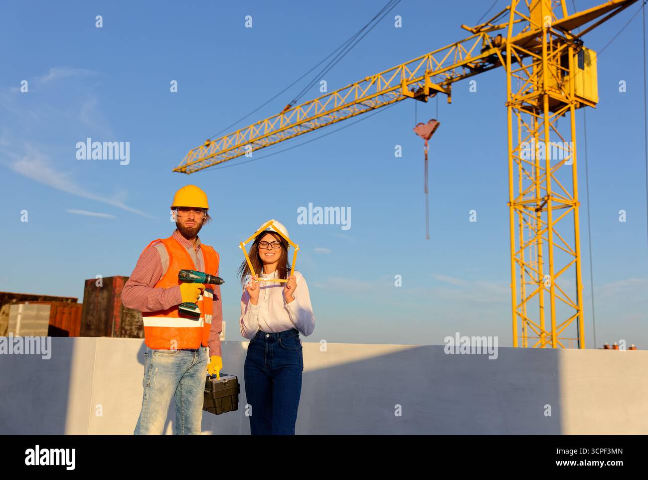 Construction workers are posing at building site holding folding ruler ...
