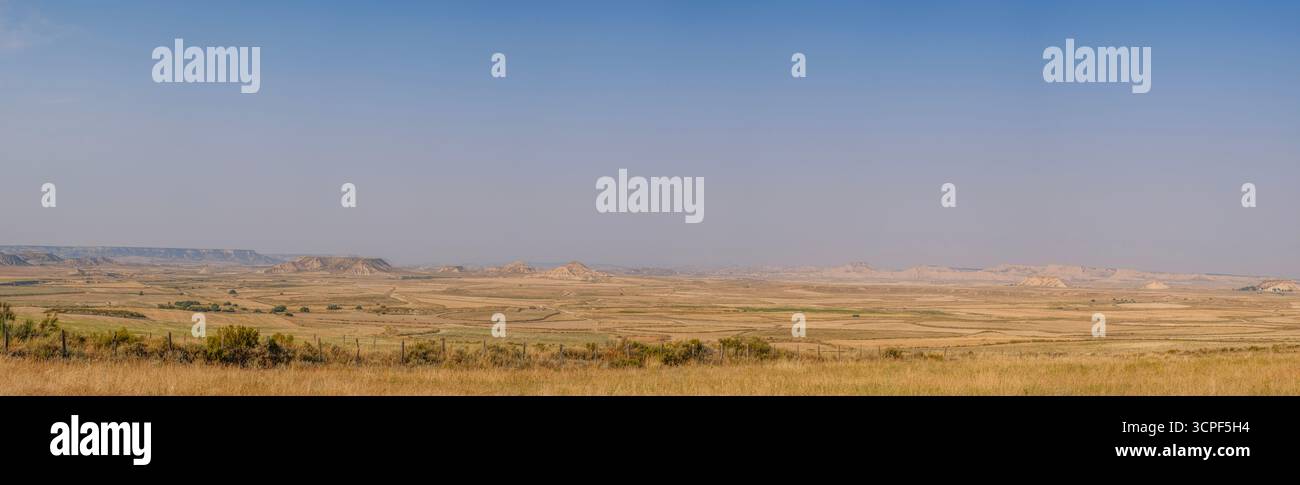 Panoramic View of Bardenas Reales Desert Landscape in Navarra Spain. Badlands with multiple rock formations, golden grasslands, semi-arid wilderness Stock Photo