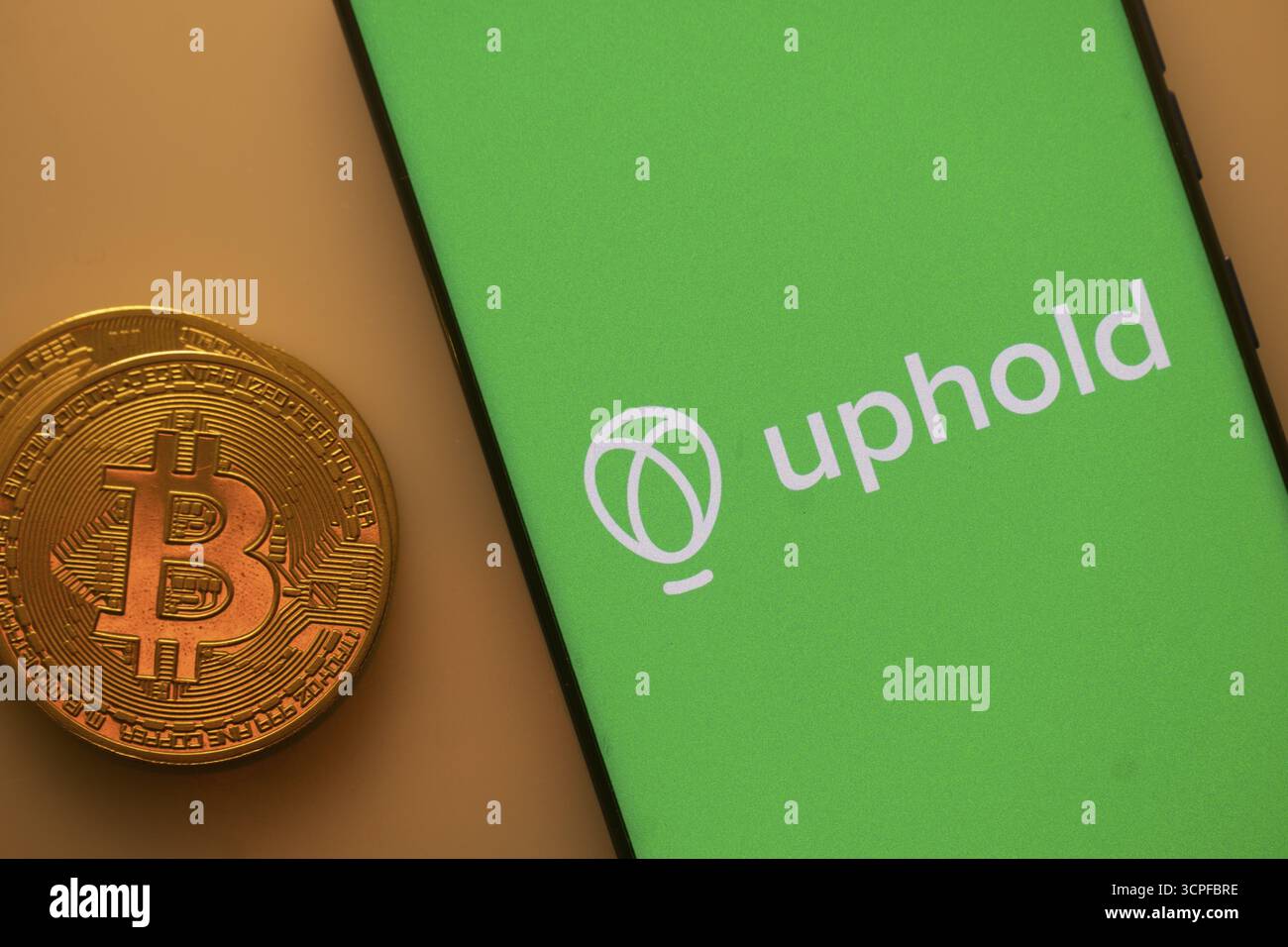 A Bitcoin coin next to an Uphold logo on a green background Stock Photo -  Alamy