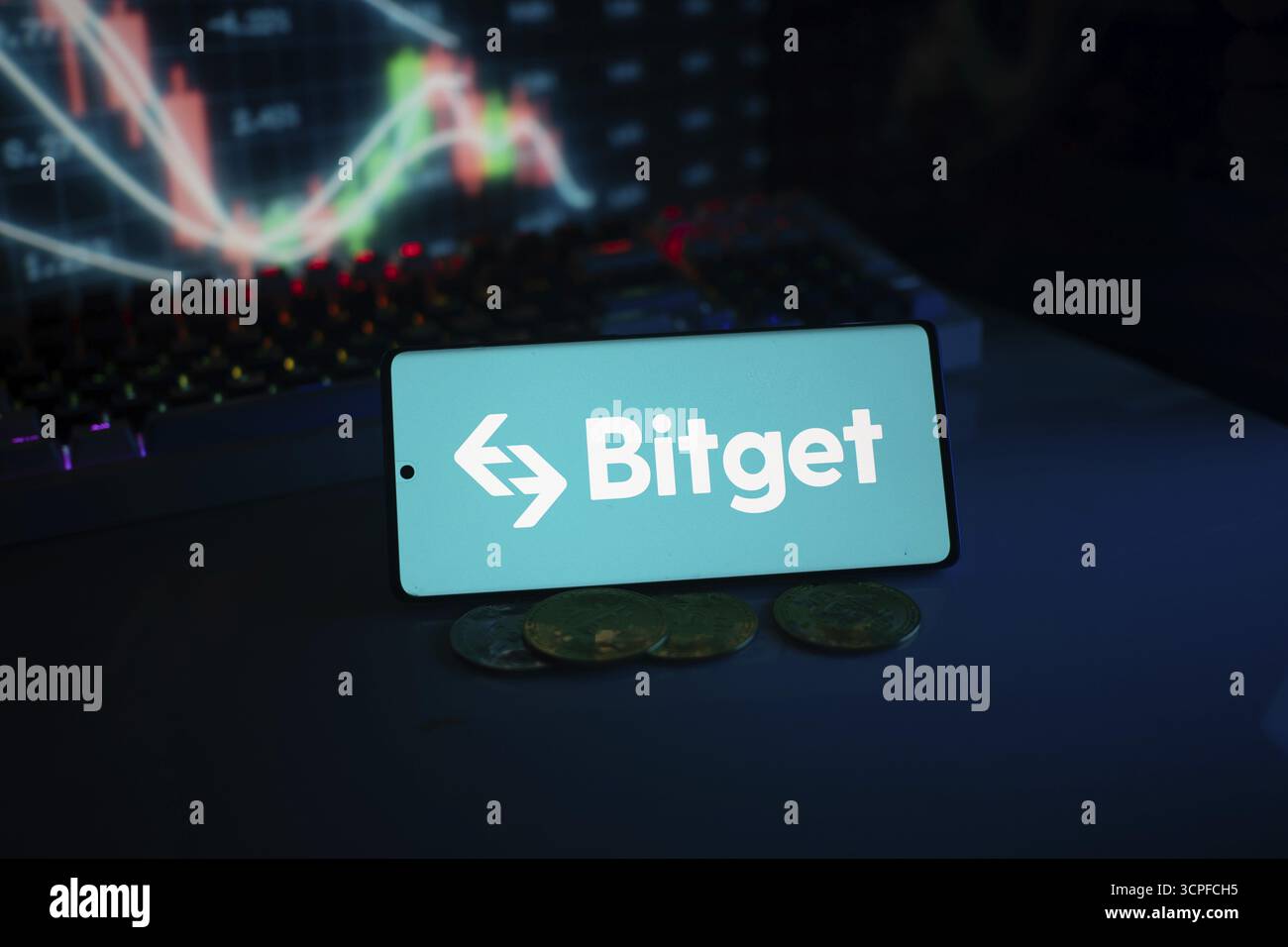 Bitget logo on smartphone with coins and stock chart, highlighting ...