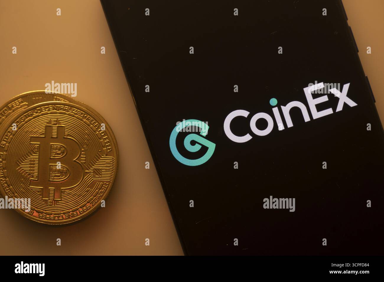CoinEx logo displayed on a smartphone screen near a Bitcoin coin on an  orange background Stock Photo - Alamy