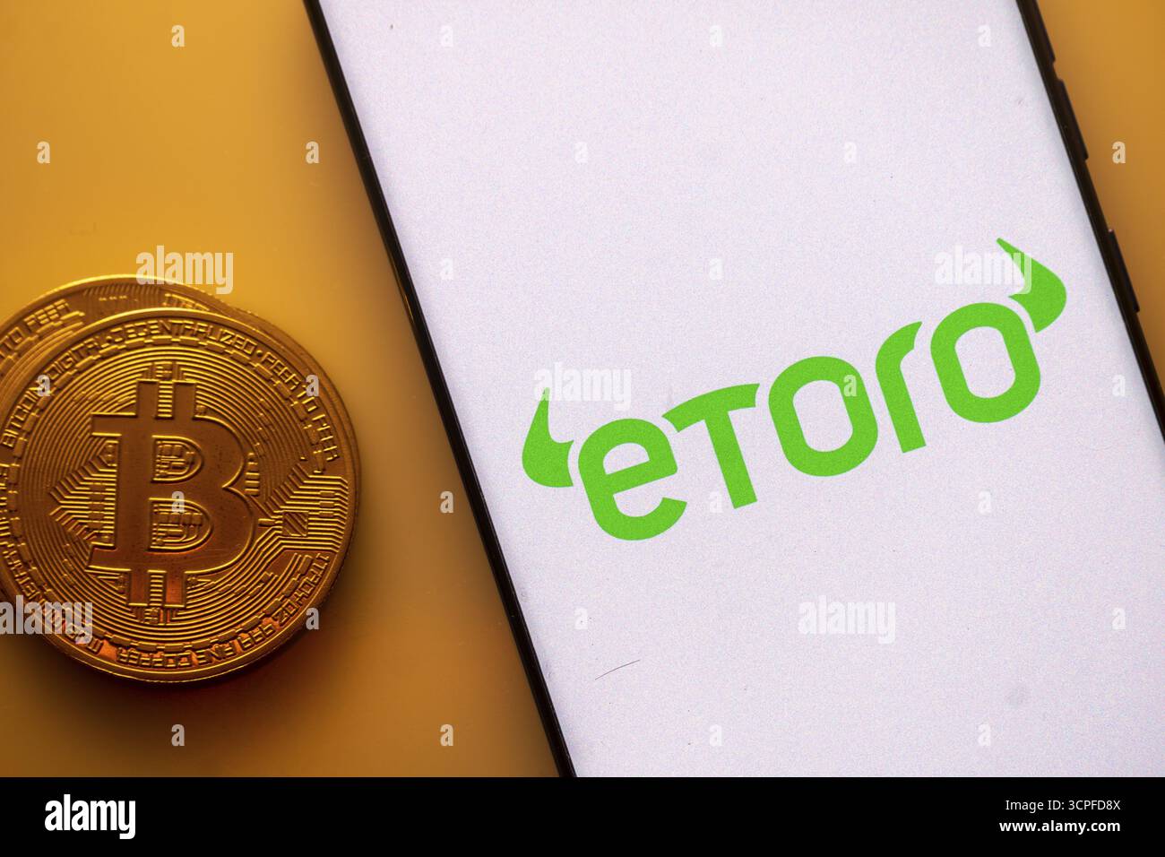 Smartphone with Etoro logo with Bitcoin coin on yellow background. Trading  platform, investing in stocks and cryptocurrencies Stock Photo - Alamy