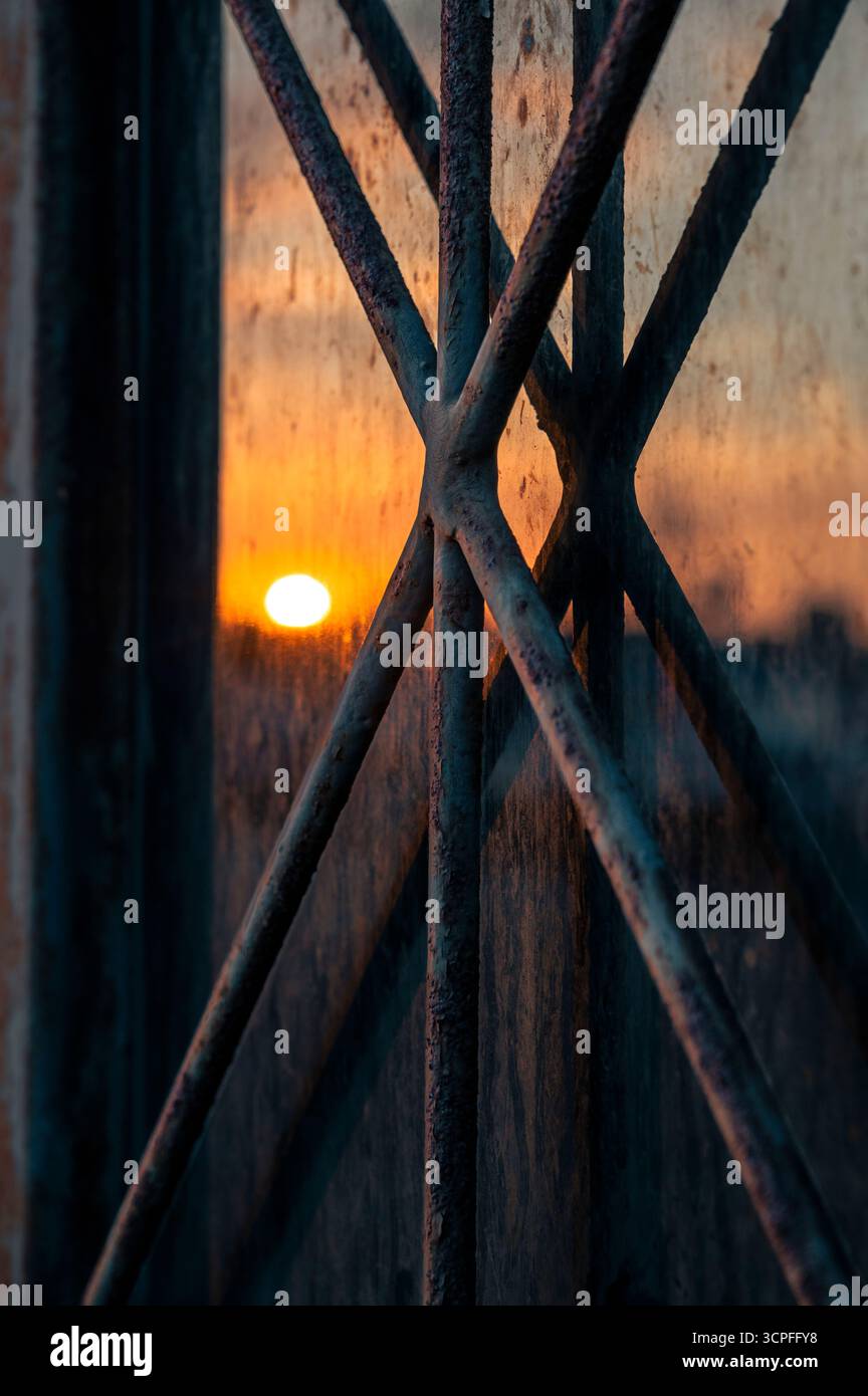 Rusty window metal bars reflection at sunrise - Degraded city Stock Photo