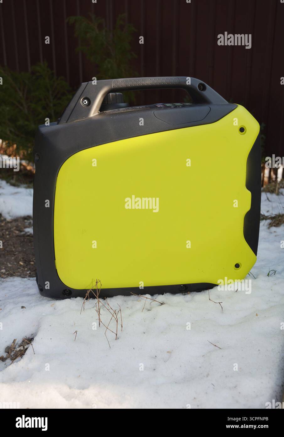 Portable inverter generator stands in the garden in the snow Stock Photo