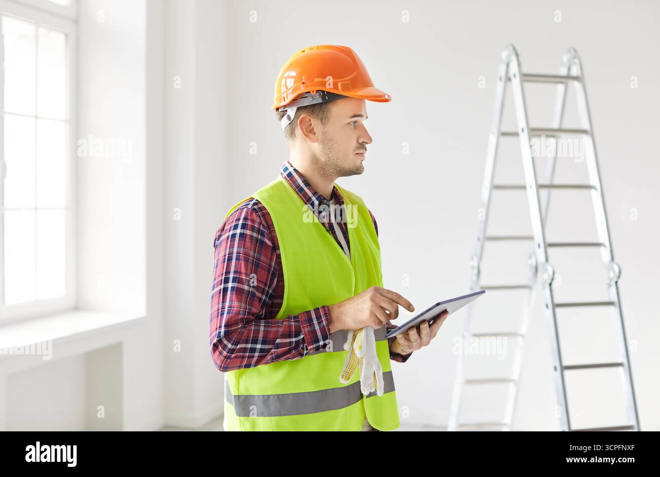 Contractor Planning Renovation Using Tablet Pc And Estimating Costs Stock Photo