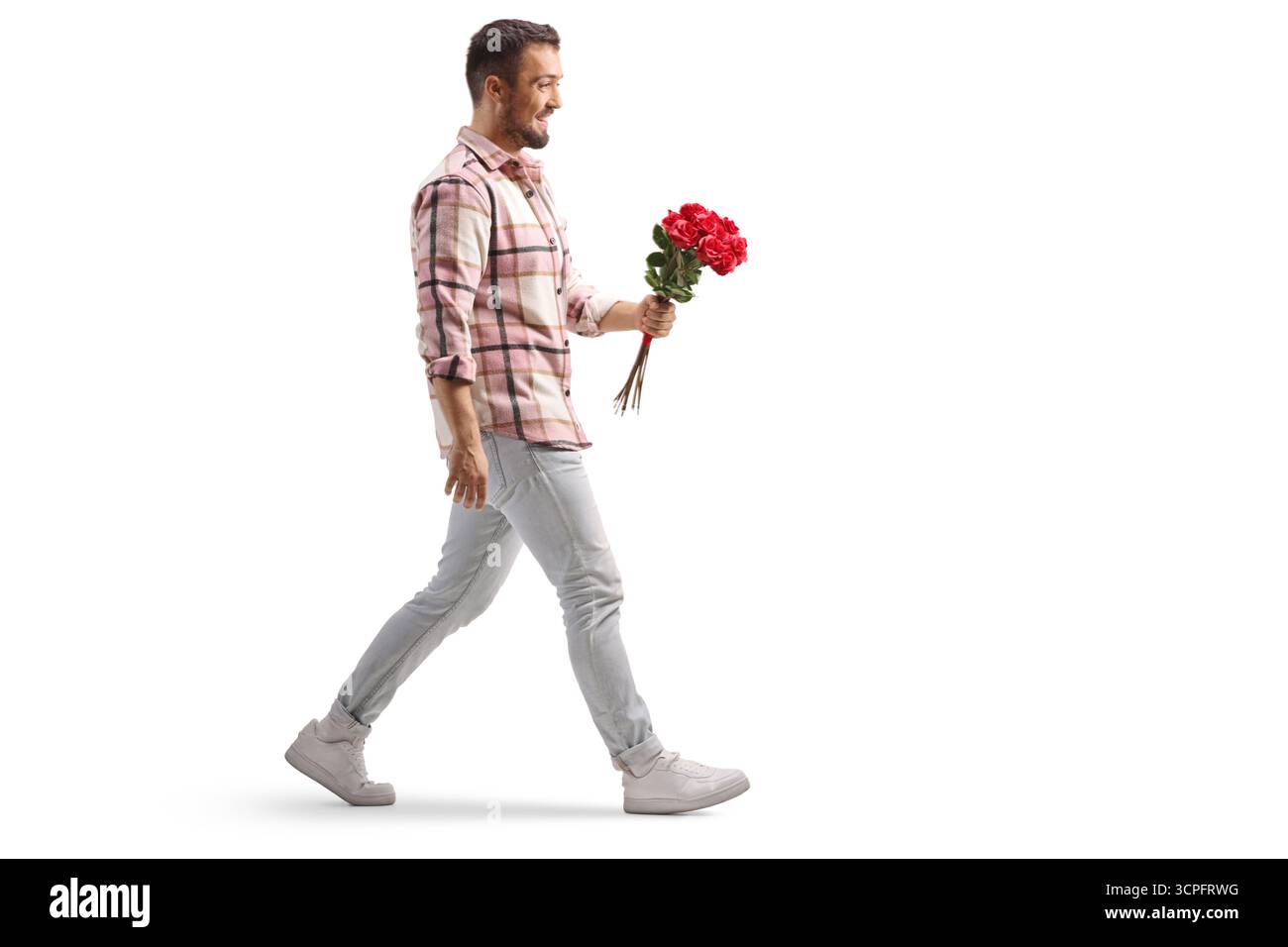 Full length profile shot of a smiling man holding a bunch of red roses and walking isolated on white background Stock Photo