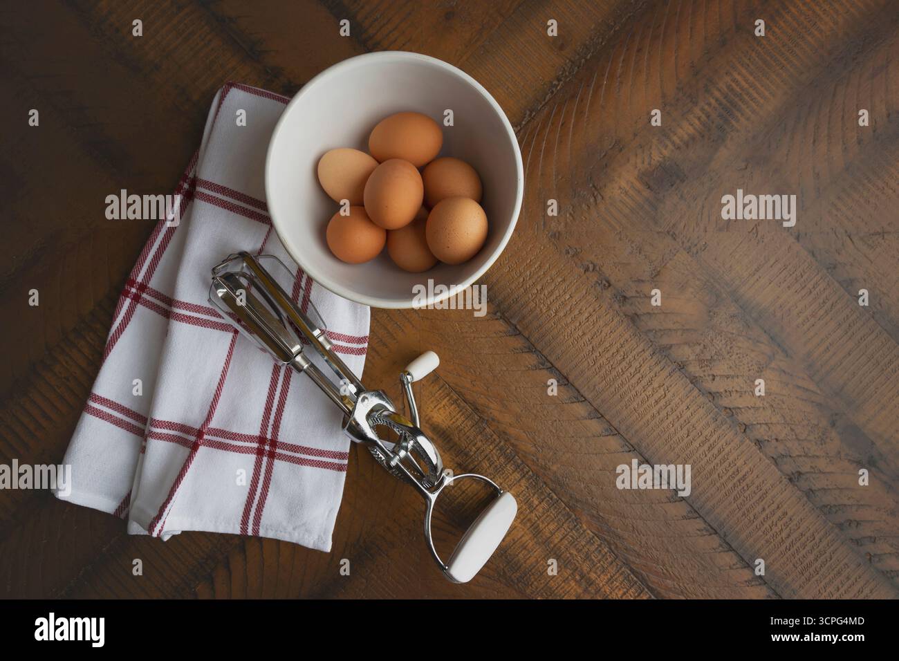 Overhead view of brown eggs in white bowl on rustic wood table Stock Photo