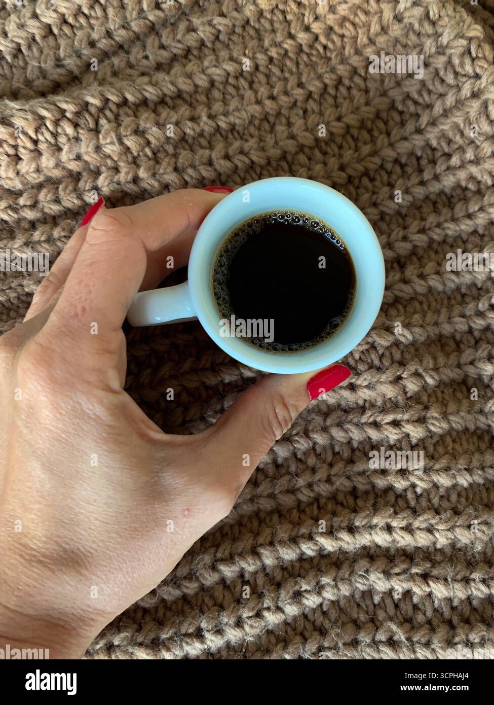 Female hand holding cup of coffee on autumn background. Brown sweater and coffee. Autumn mood flat lay. Concept cozy coffee cup. Top view. Cozy autumn - Smartphone Captured Stock Image