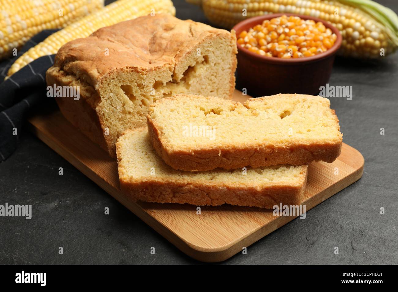 Freshly baked cornbread, cobs and seeds on black table, closeup Stock Photo