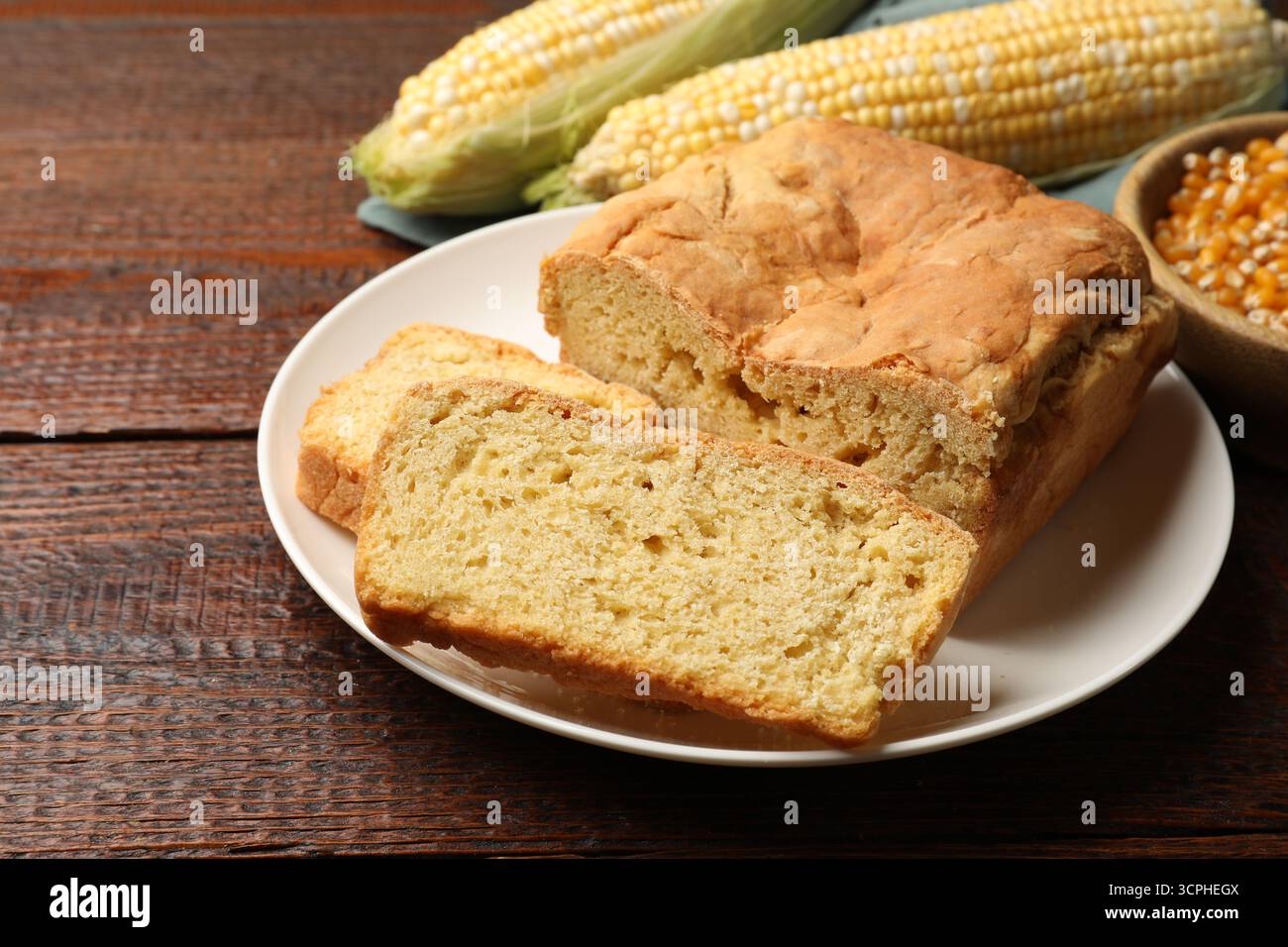 Freshly baked cornbread, cobs and seeds on wooden table, closeup Stock Photo