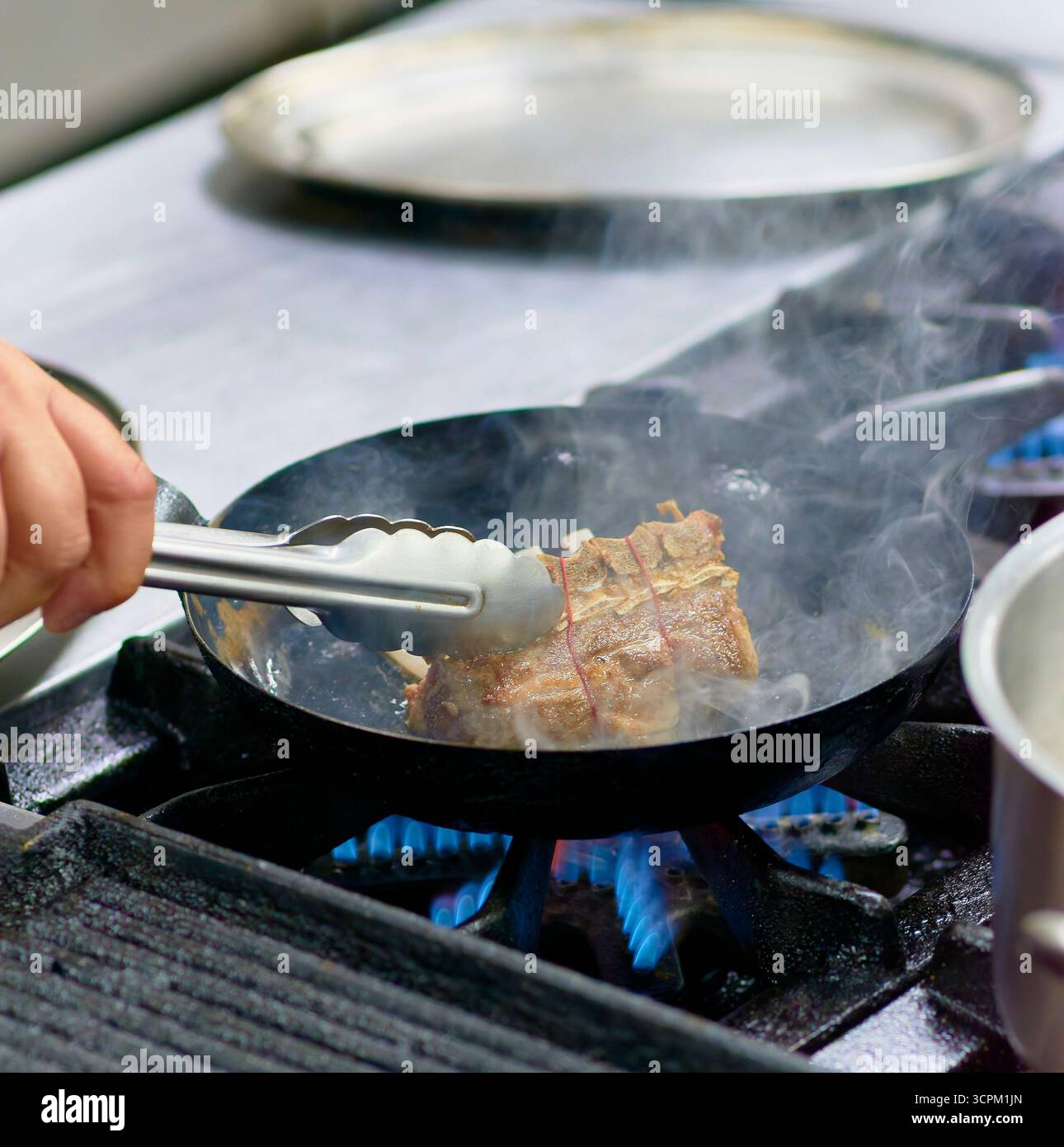 Meat browning in an iron skillet over high heat. Active cooking, metal ...