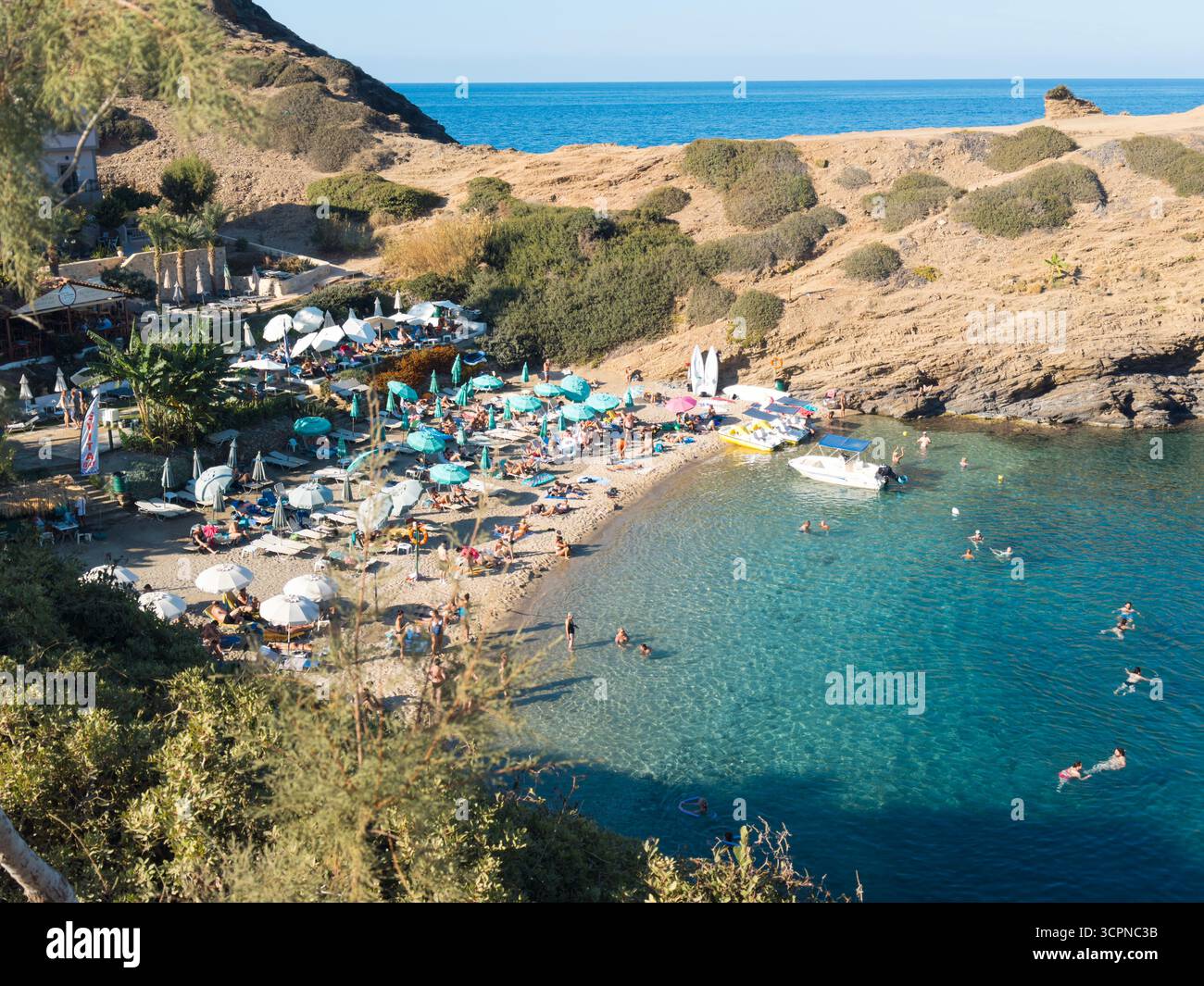 Scenic Karavostasi beach in Bali, Crete, with turquoise waters, sunbathers, and boats along the rocky Mediterranean coastline. - Smartphone Captured Stock Image
