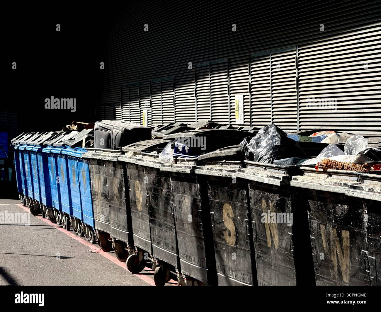 Black and blue waste bins lined up in Deansgate Square complex, Manchester - Smartphone Captured Stock Image