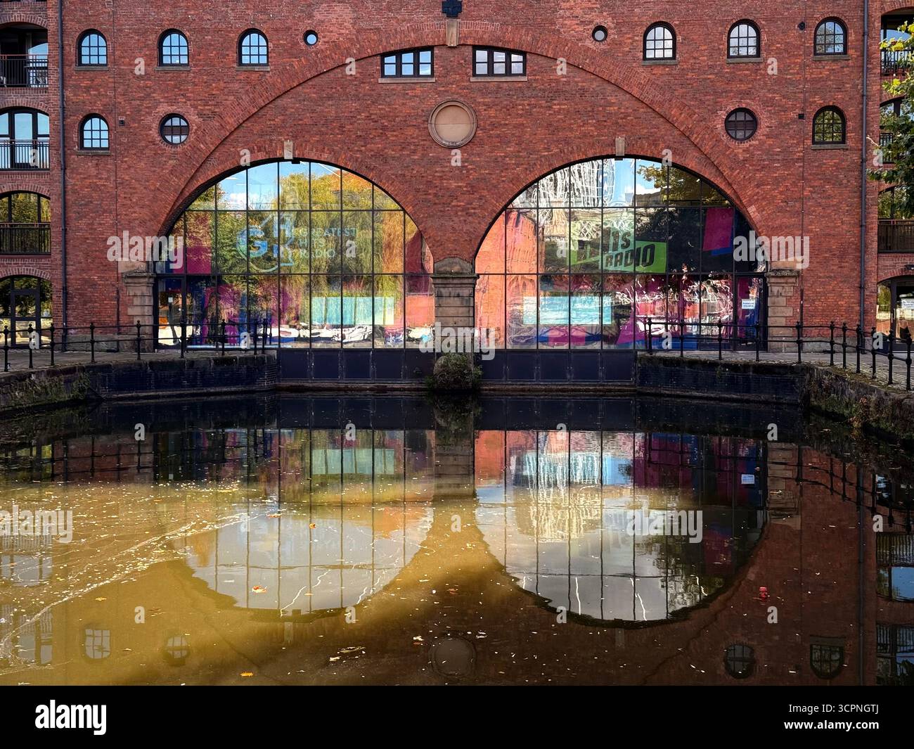 Castle Wharf by Medlock river. Reflections of arched windows in pond off the river in Castlefield Manchester - Smartphone Captured Stock Image