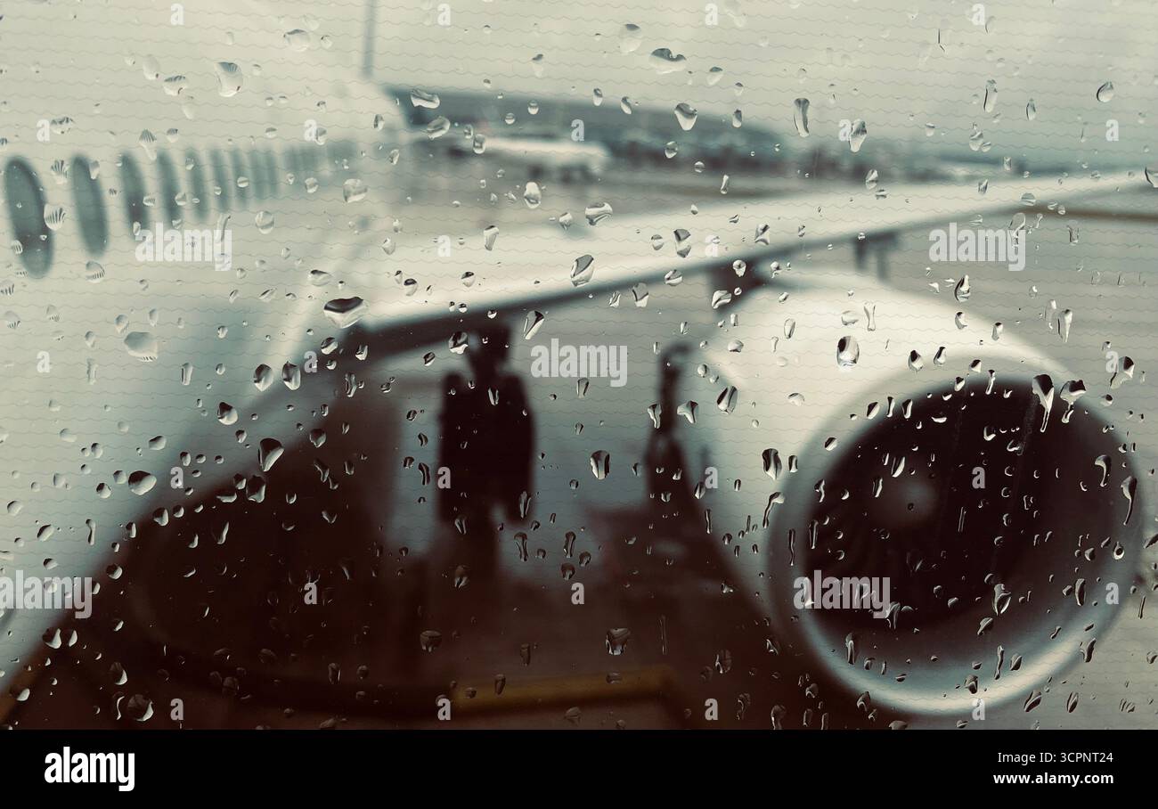 Raindrops on Window with Blurred Airplane Engine and Wing in Rainy Weather - Smartphone Captured Stock Image